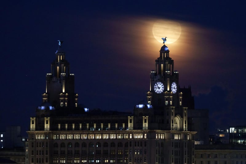 A full blue moon rises behind the Royal Liver Building and the Liver Bird statues in Liverpool (Photo by Christopher Furlong/Getty Images)