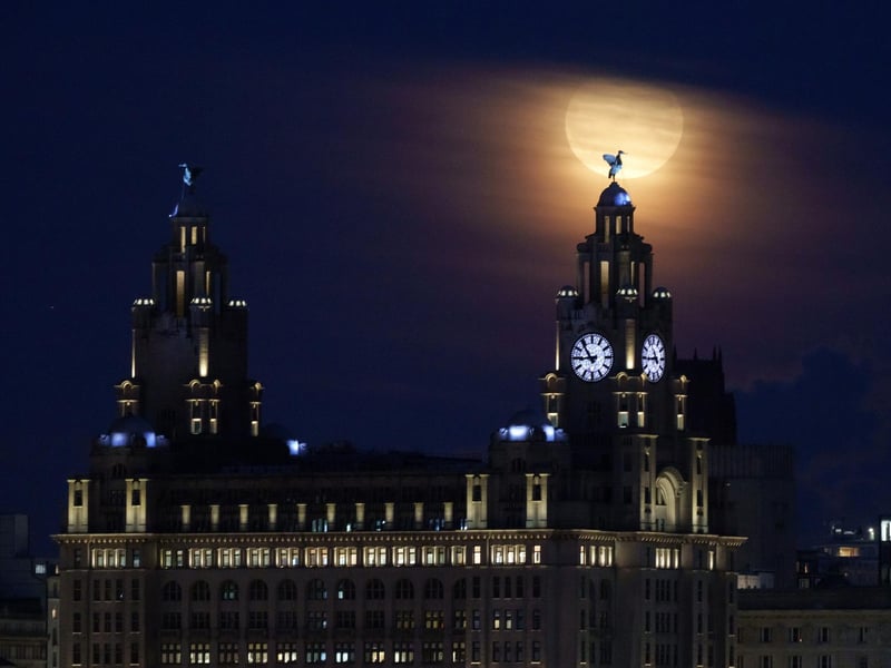 A full blue moon rises behind the Royal Liver Building and the Liver Bird statues in Liverpool (Photo by Christopher Furlong/Getty Images)