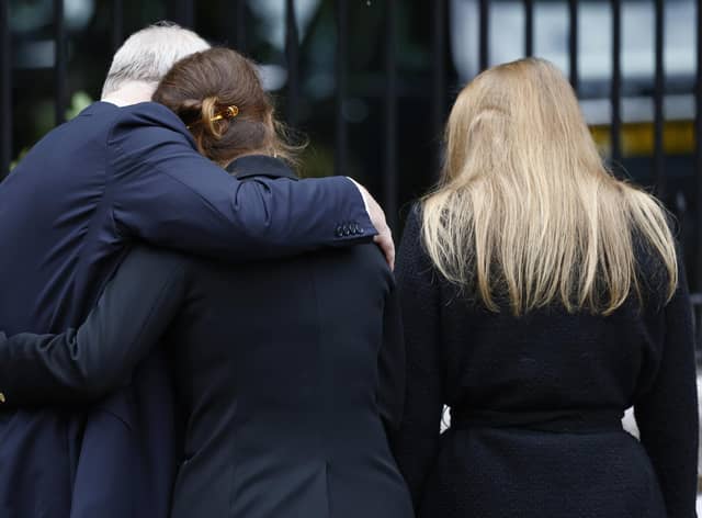 Prince Andrew, Duke of York puts his arm around Princess Eugenie of York and Princess Beatrice of York