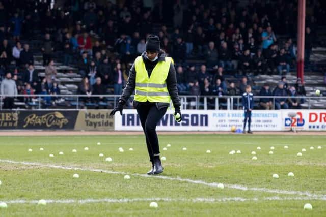 A steward removes tennis balls from the Dens Park pitch during one of the stoppages in play forced by Rangers fans' protests on Sunday. (Photo by Alan Harvey / SNS Group)