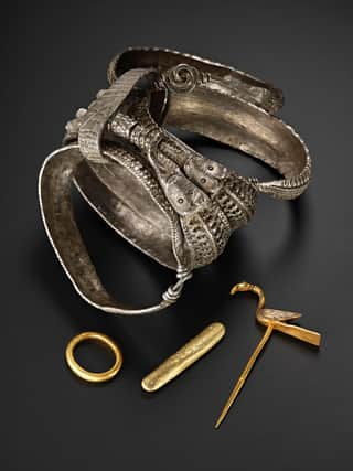 Silver arm rings and gold items, including a bird pin, found among the hoard which contains around 100 objects in total. PIC: NMS.