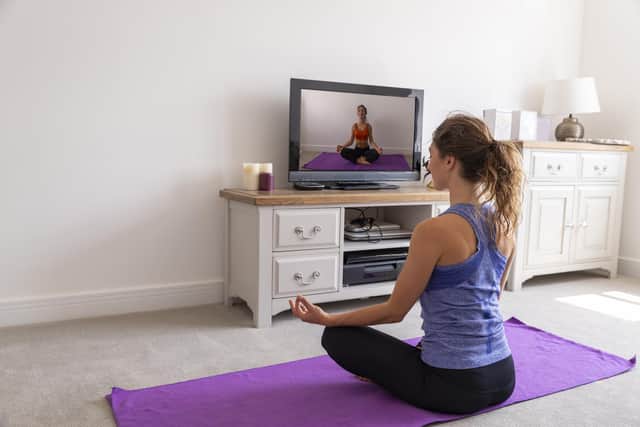 A young woman at home practicing yoga in front of the TV