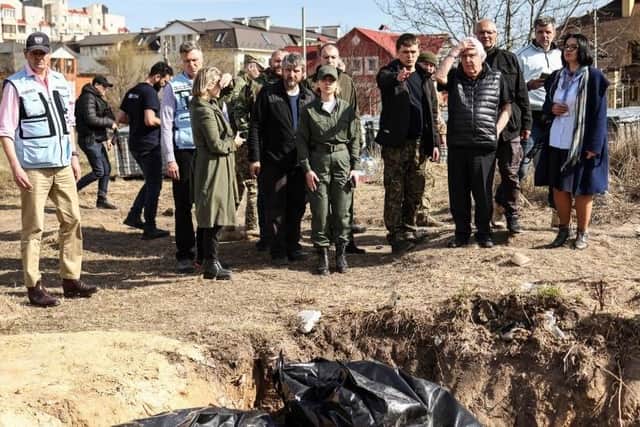 UN humanitarian chief Martin Griffiths (5th R) reacts at the site of a mass grave that Ukrainians had dug near a church during his three-hour visit to Bucha, a day after he visited Moscow, where he met with officials to discuss the humanitarian situation in Ukraine.