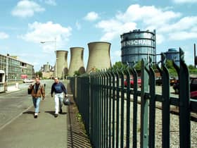 Two men walk through the gates of Ravenscraig steel works aster the last shift before the plant finally closes in June 1992.