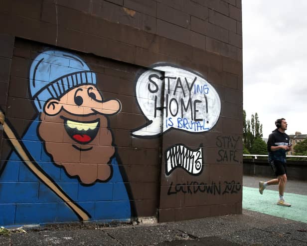 A jogger passing coronavirus related graffiti in Glasgow.