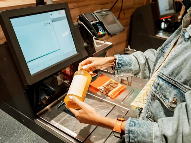 A customer scans and pays for a bottle of juice from a supermarket at an automated self-service checkout terminal. PIC: Adobe