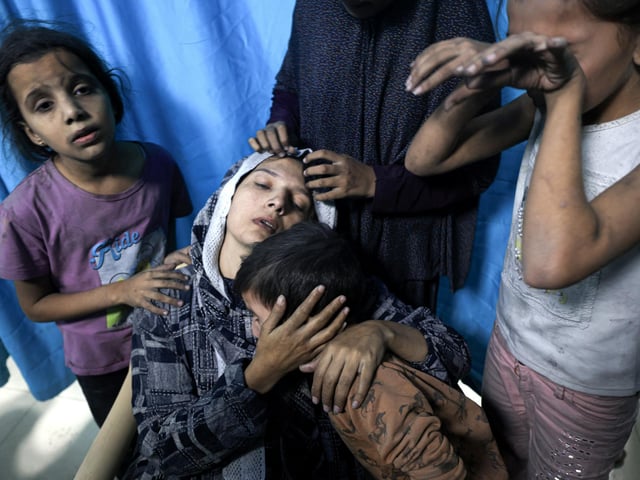 A wounded Palestinian woman from the Baraka family is surrounded by her children upon their arrival at Nasser Hospital in Khan Yunis in the southern Gaza Strip following Israeli air strikes that hit their building