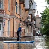 A local resident sails on a paddle board during an evacuation from a flooded area in Kherson, Ukraine, following damages sustained at Kakhovka hydroelectric power plant dam.