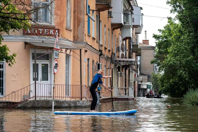 A local resident sails on a paddle board during an evacuation from a flooded area in Kherson, Ukraine, following damages sustained at Kakhovka hydroelectric power plant dam.