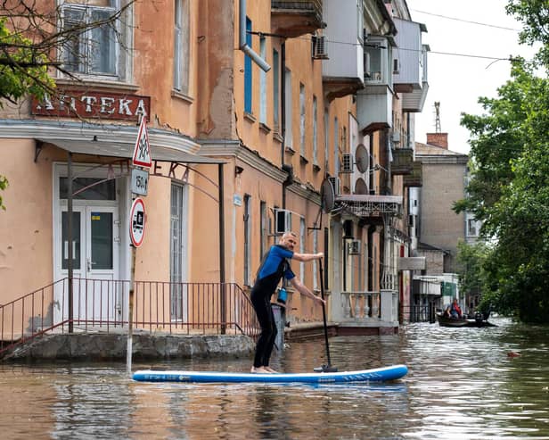 A local resident sails on a paddle board during an evacuation from a flooded area in Kherson, Ukraine, following damages sustained at Kakhovka hydroelectric power plant dam.