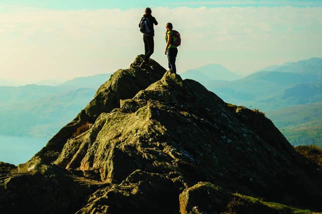 Two female hikers on top of the mountain enjoying valley view, Ben A'an, Loch Katrina, Highlands. Image: Andrea Obzerova