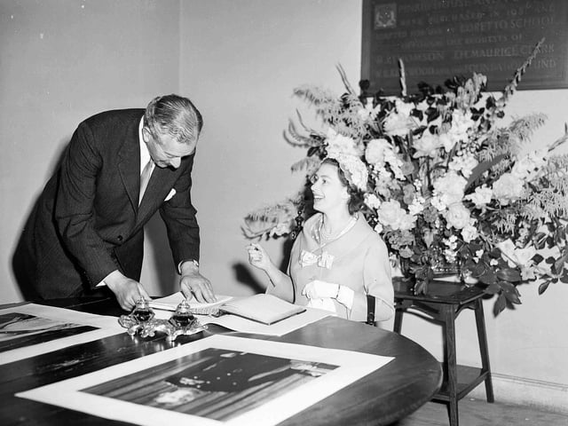 Queen Elizabeth II signs the visitors' book of Loretto School, alongside headmaster Mr David Forbes Mackintosh, on July 1, 1958.