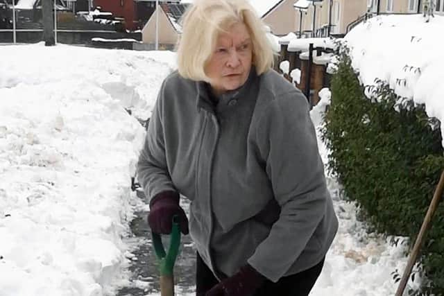 85-years-old Isabel Nicholson clearing snow outside her home in Redding.