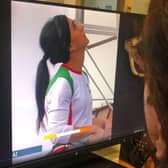 A woman looks at a screen displaying a video of an international climbing competition is Seoul, South Korea, during which Iranian climber Elnaz Rekabi competes without a hijab.
