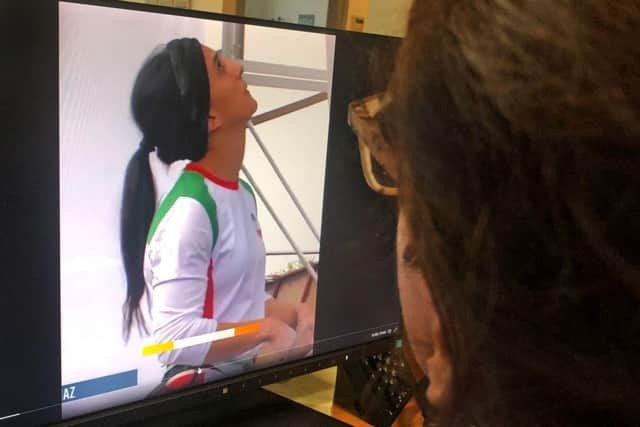 A woman looks at a screen displaying a video of an international climbing competition is Seoul, South Korea, during which Iranian climber Elnaz Rekabi competes without a hijab.