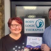 Sports Massage Therapist Jacquie Gibson and Duncan Thomson, Director of Body Logic Therapies accept their Respitality Donation Certificate from Quarriers for offering a therapy to local unpaid carer Jean Meikle