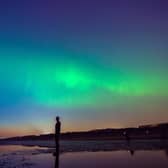 The aurora borealis, also known as the northern lights, glow on the horizon at Another Place by Anthony Gormley, Crosby Beach, Liverpool , Merseyside .