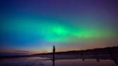 The aurora borealis, also known as the northern lights, glow on the horizon at Another Place by Anthony Gormley, Crosby Beach, Liverpool , Merseyside .