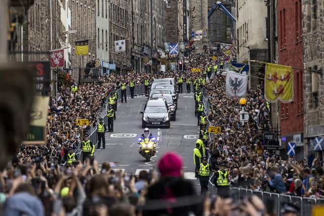 Members of the public gather on the Royal Mile in Edinburgh to watch the hearse carrying the coffin of Queen Elizabeth II, draped with the Royal Standard of Scotland, as it completes its journey from Balmoral to the Palace of Holyroodhouse in Edinburgh, where it will lie in rest for a day.