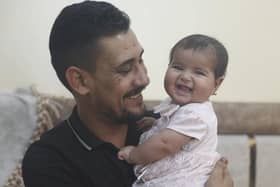 Khalil al-Sawadi plays with his adopted daughter Afraa in Jinderis, Syria