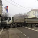 A man passes by a barricade made of trucks loaded with stones that was erected during the night on a street in northern, Serb-dominated part of ethnically divided town of Mitrovica, Kosovo. Picture: AP Photo/Bojan Slavkovic