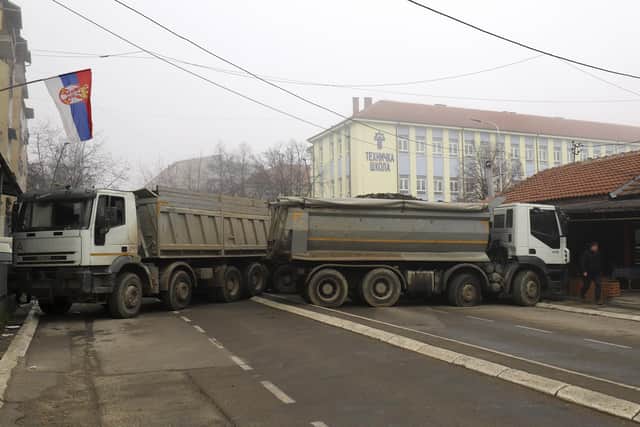 A man passes by a barricade made of trucks loaded with stones that was erected during the night on a street in northern, Serb-dominated part of ethnically divided town of Mitrovica, Kosovo. Picture: AP Photo/Bojan Slavkovic