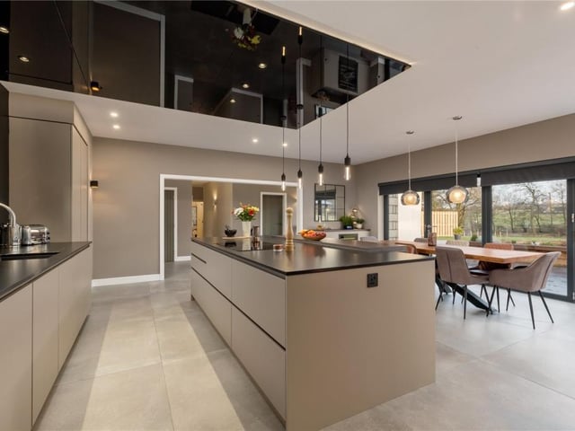 The kitchen is fitted with a range of contemporary kitchen units, central breakfast bar, bi-folding doors to the patio, feature ceiling, and numerous integrated appliances.