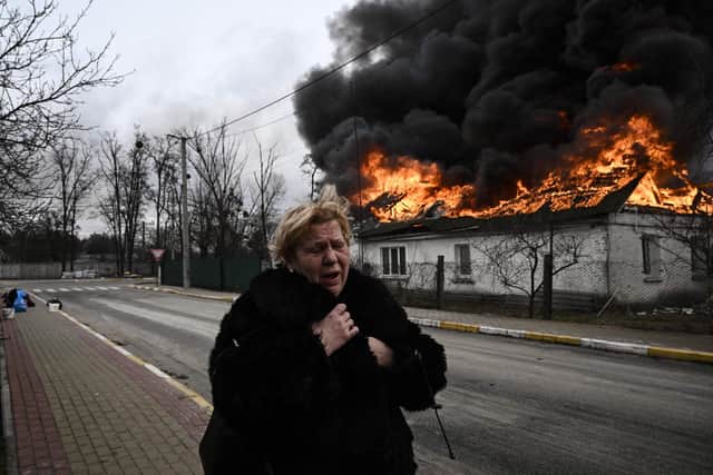 A woman flees as a house burns after being shelled by Russian forces in the city of Irpin, outside Kyiv, on March 4, 2022 (Picture: Aris Messinis/AFP via Getty Images)