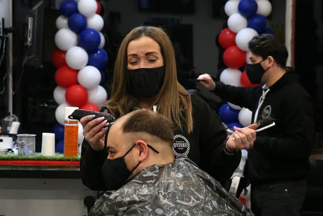 Barber Maggie McGillivray trims Sam Rosenblom's hair at Tony Mann's Barber Shop in Giffnock near Glasgow as barbers reopen across Scotland.