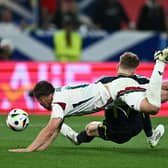 Scotland's Stuart Armstrong falls under the challenge of Hungary defender Willi Orban but no penalty was awarded. (Photo by FABRICE COFFRINI/AFP via Getty Images)