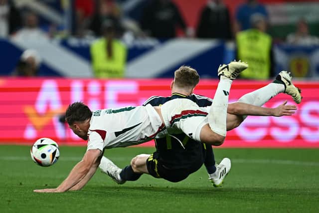 Scotland's Stuart Armstrong falls under the challenge of Hungary defender Willi Orban but no penalty was awarded. (Photo by FABRICE COFFRINI/AFP via Getty Images)