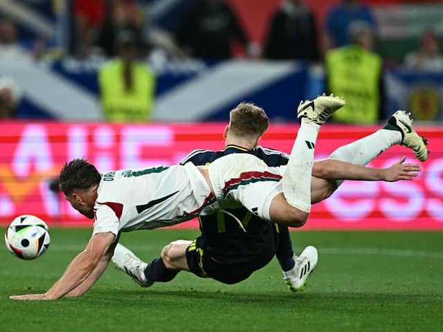 Scotland's Stuart Armstrong falls under the challenge of Hungary defender Willi Orban but no penalty was awarded. (Photo by FABRICE COFFRINI/AFP via Getty Images)