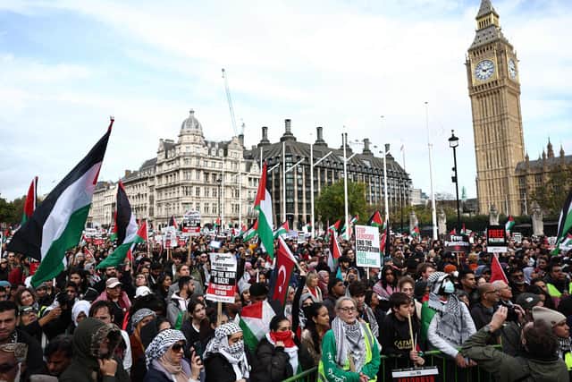 People hold up placards and wave Palestinian flags in Parliament Square after taking part in a March For Palestine in London. Picture: Henry Nicholls/AFP