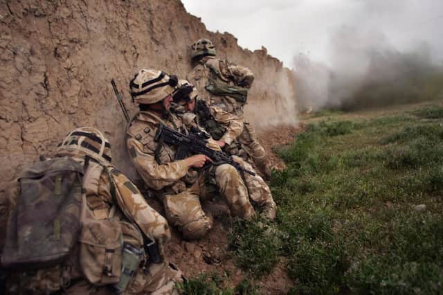 Royal Marines take cover while blasting a whole in a wall during an anti-Taliban operation near Kajaki in the Afghan province of Helmand in 2007 (Picture: John Moore/Getty Images)