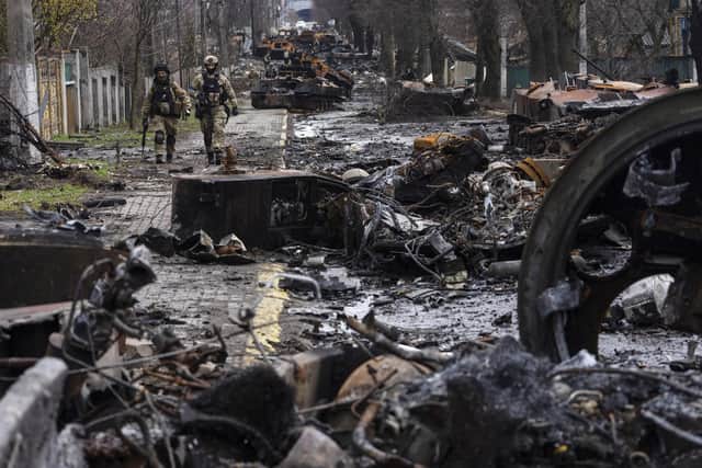 Soldiers walk amid destroyed Russian tanks in Bucha, on the outskirts of Kyiv