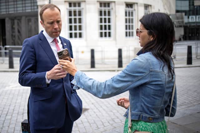 Health Secretary Matt Hancock, looks at the phone of his aide Gina Coladangelo as they leave the BBC in central London on June 6, 2021.