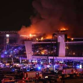 Emergency services vehicles are seen outside the burning Crocus City Hall concert hall following the attack. (Photo by STRINGER/AFP via Getty Images)