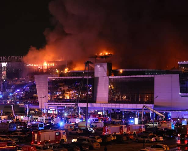 Emergency services vehicles are seen outside the burning Crocus City Hall concert hall following the attack. (Photo by STRINGER/AFP via Getty Images)