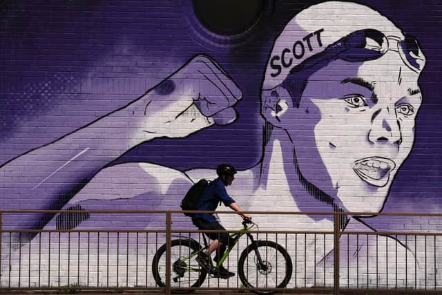 A cyclist passes a mural of swimmer Duncan Scott, commissioned ahead of the Glasgow 2026 Commonwealth Games, on one of the railway arches along the Clydeside Expressway in Glasgow.