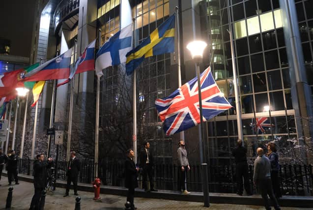 Workers at the European Parliament lower the British flag from the row of flags of EU member states outside the parliament in Brussels on January 31, 2020 - Brexit day