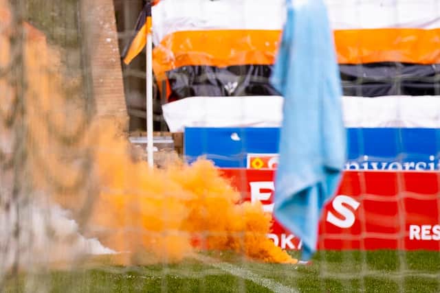 An orange flare billows out smoke as it lies on the Tannadice turf. Picture: SNS