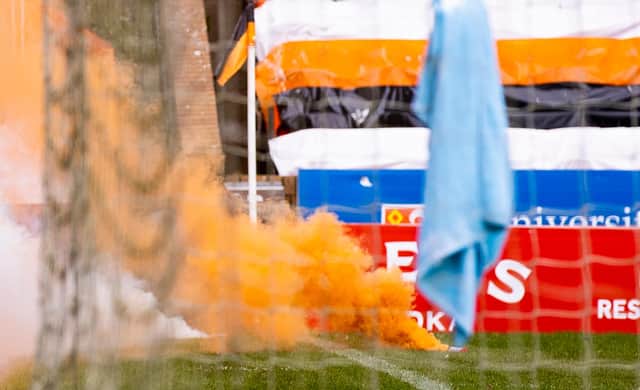 An orange flare billows out smoke as it lies on the Tannadice turf. Picture: SNS