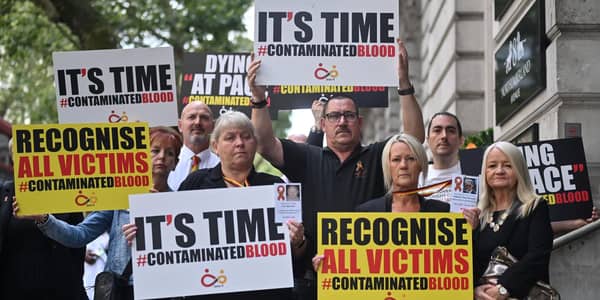 Demonstrators hold placards reading message related to the NHS infected blood scandal as Britain's Prime Minister Rishi Sunak is questioned by Infected Blood Inquiry, in London, on July 26, 2023. (Picture: Justin Tallis/AFP via Getty Images)