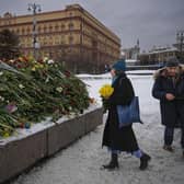 People lay flowers paying respects to Alexei Navalny at a monument, a large boulder from the Solovetsky islands, where the first camp of the Gulag political prison system was established (Picture: AP Photo/Alexander Zemlianichenko)