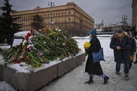 People lay flowers paying respects to Alexei Navalny at a monument, a large boulder from the Solovetsky islands, where the first camp of the Gulag political prison system was established (Picture: AP Photo/Alexander Zemlianichenko)