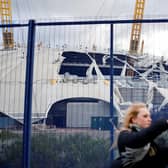A pedestrian takes a selfie with the wind-damaged roof of The O2 Arena, in London after Storm Eunice battered the country