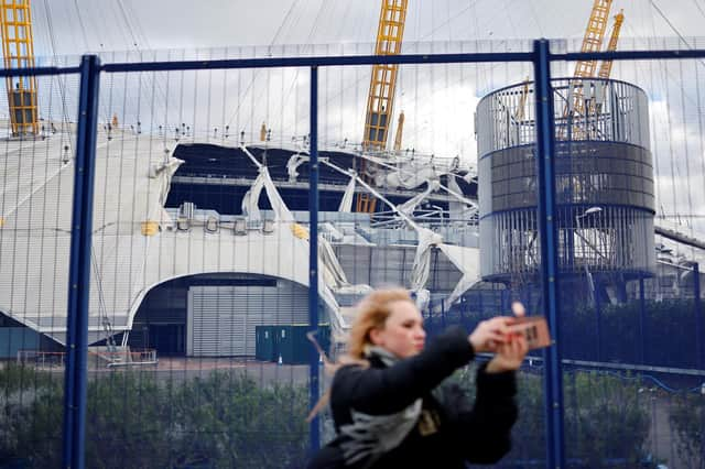 A pedestrian takes a selfie with the wind-damaged roof of The O2 Arena, in London after Storm Eunice battered the country