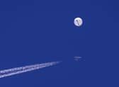 A large balloon drifts above the Atlantic Ocean, just off the coast of South Carolina, with a fighter jet and its contrail seen below it. Picture: Chad Fish via AP