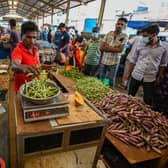 People buy vegetables at a market after authorities relaxed the ongoing curfew for a few hours in Colombo on Thursday.