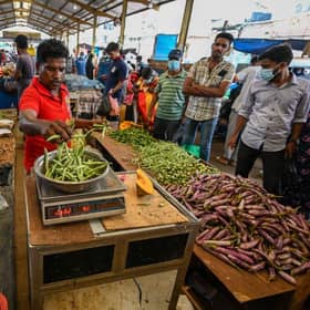 People buy vegetables at a market after authorities relaxed the ongoing curfew for a few hours in Colombo on Thursday.